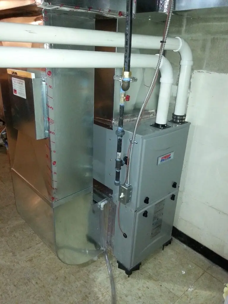 A commercial HVAC unit in a basement with pipes and electrical connections.
